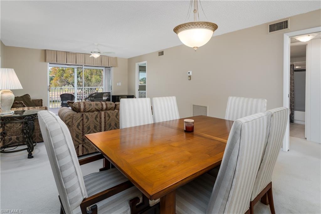 Dining area with a ceiling fan, visible vents, and light colored carpet