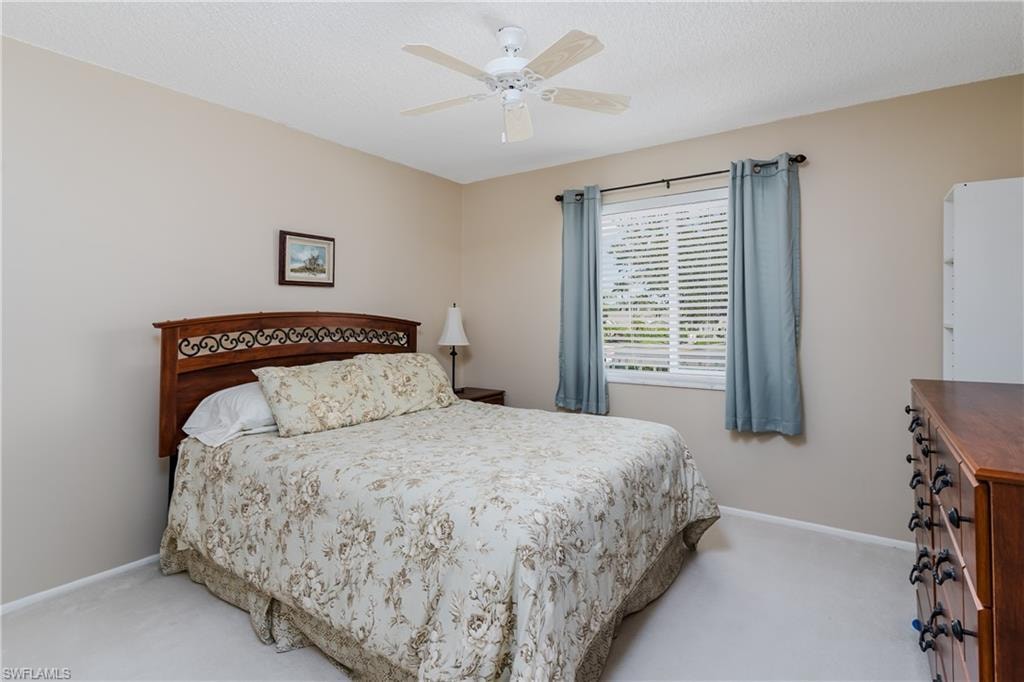 Bedroom with ceiling fan, carpet floors, and baseboards