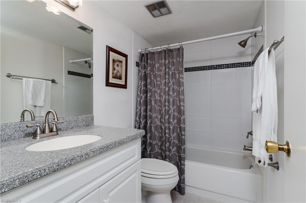 Full bathroom with tile patterned floors, visible vents, toilet, vanity, and shower / tub combo