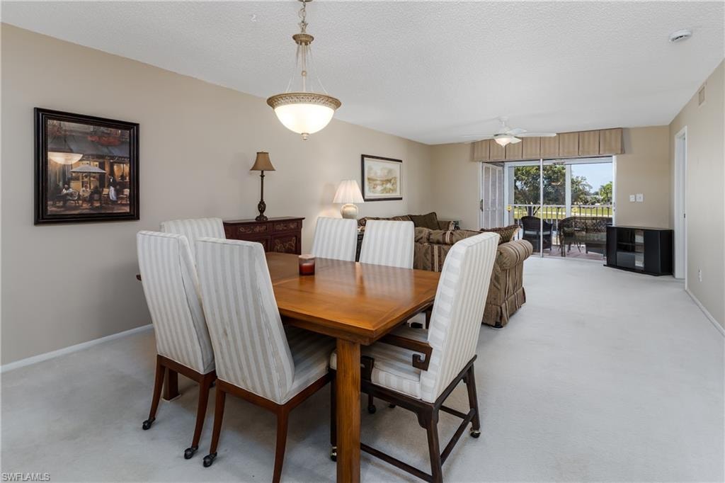 Dining space with ceiling fan, baseboards, visible vents, and light colored carpet