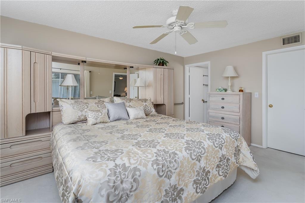Bedroom featuring light colored carpet, ceiling fan, a textured ceiling, and visible vents
