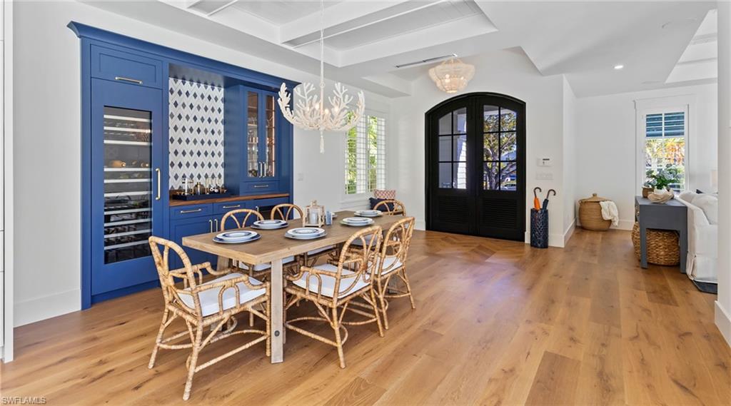 Dining room featuring beverage cooler, suspended lighting, light wood finished floors, beamed ceiling, and french doors