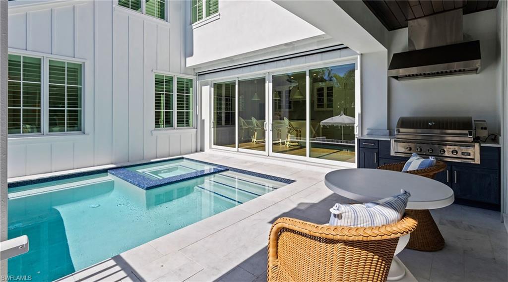 Combined pool / hot tub featuring a patio and exterior kitchen