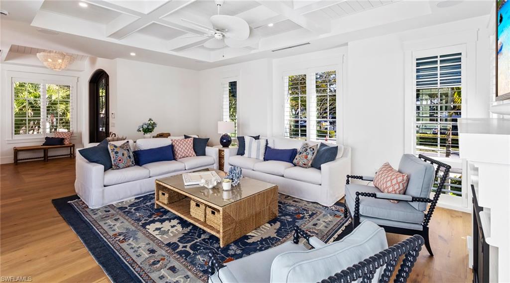 Living area with coffered ceiling, wood finished floors, ceiling fan, recessed lighting, and arched walkways