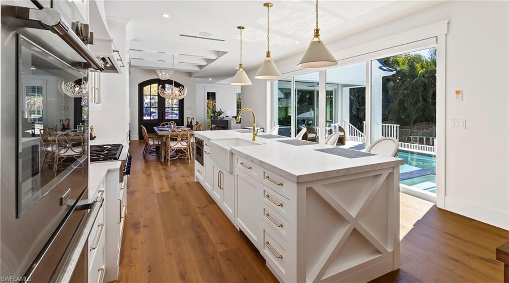 Kitchen featuring stainless steel appliances, a center island with sink, white cabinets, and dark wood finished floors