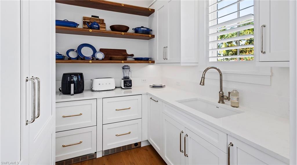 Kitchen featuring white cabinetry, light stone countertops, and open shelves