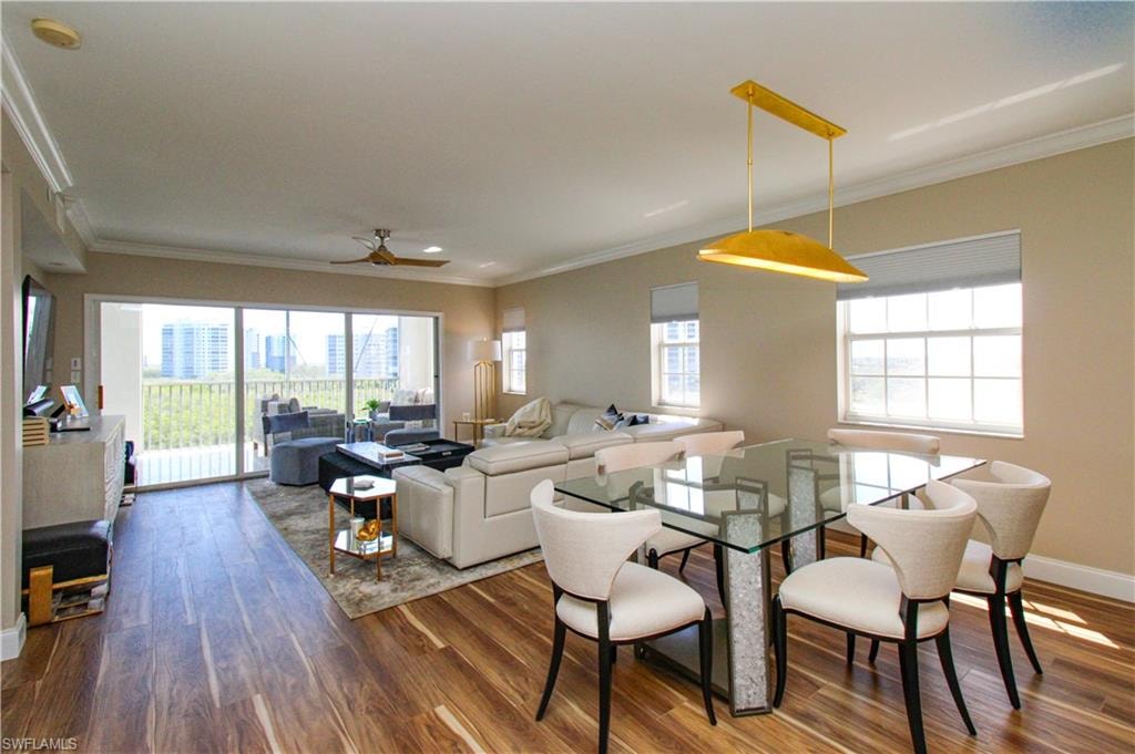 Dining space with dark wood-type flooring, crown molding, and a healthy amount of sunlight