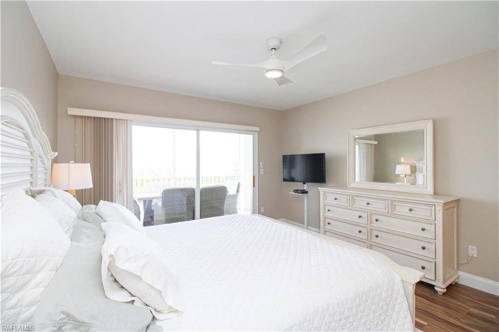 Bedroom with dark hardwood / wood-style flooring, access to outside, and ceiling fan