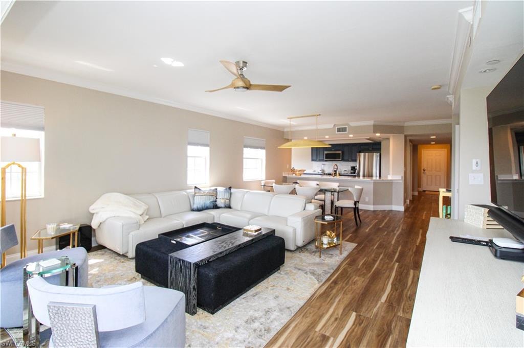 Living room with crown molding, ceiling fan, and dark hardwood / wood-style flooring