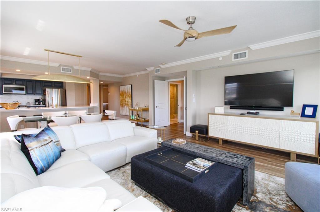 Living room with light hardwood / wood-style floors, ornamental molding, and ceiling fan