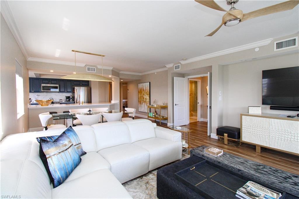 Living room with light hardwood / wood-style floors, crown molding, and ceiling fan