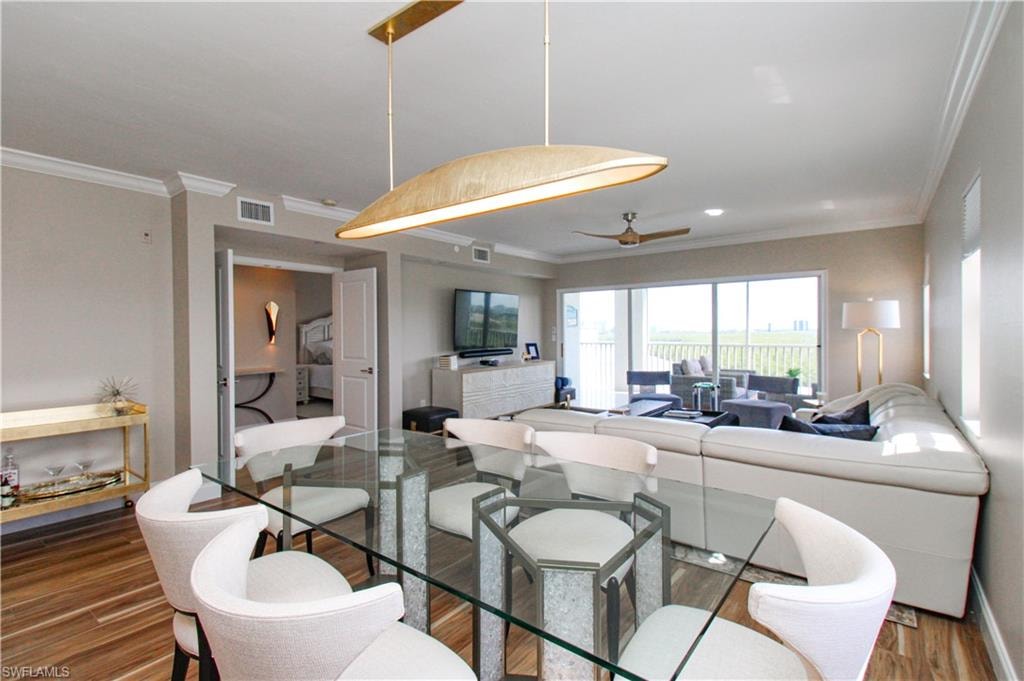 Dining room with crown molding, hardwood / wood-style floors, and ceiling fan