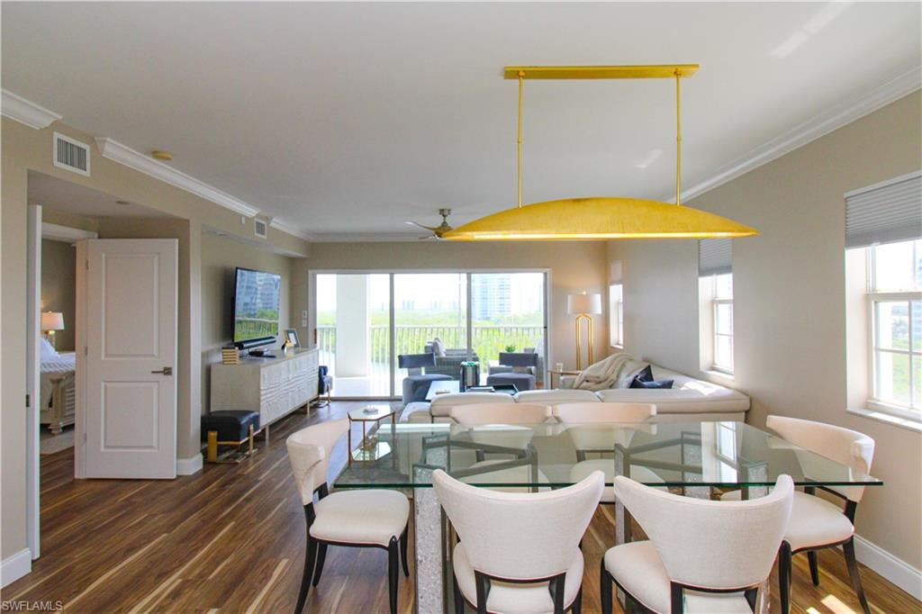 Dining space with dark wood-type flooring, crown molding, a healthy amount of sunlight, and ceiling fan