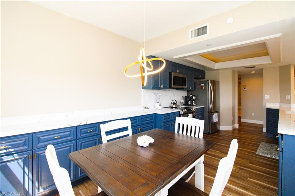 Dining room featuring a raised ceiling, an inviting chandelier, and dark hardwood / wood-style floors