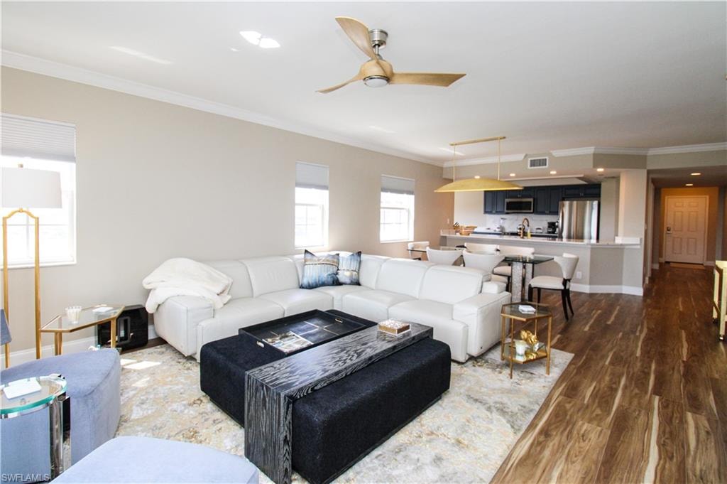 Living room with ornamental molding, ceiling fan, and dark hardwood / wood-style flooring