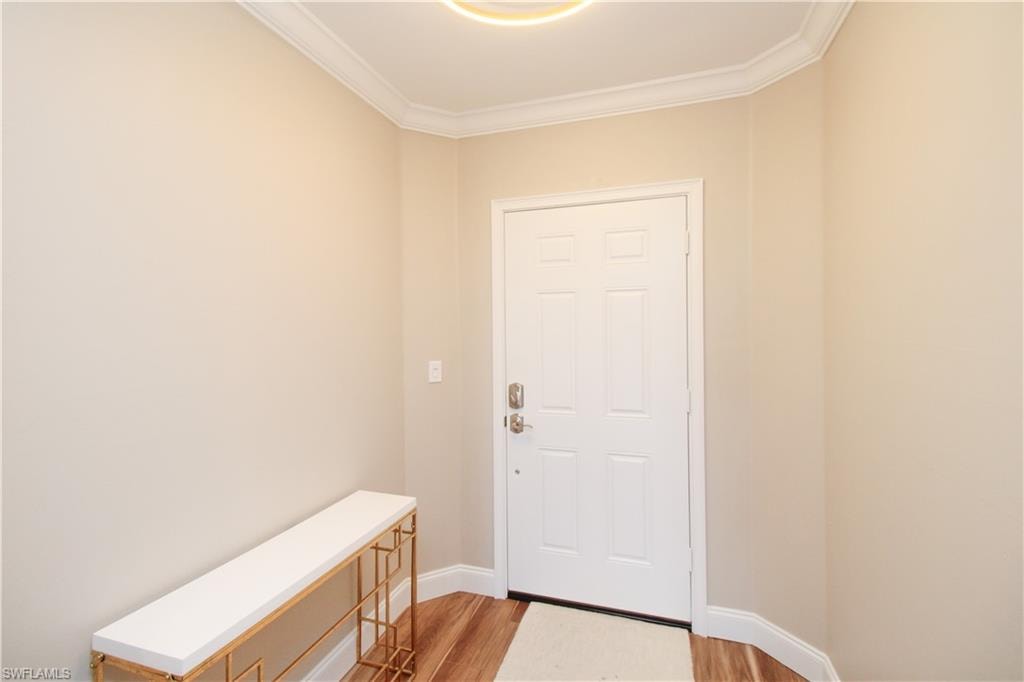 Entryway with light hardwood / wood-style flooring and crown molding