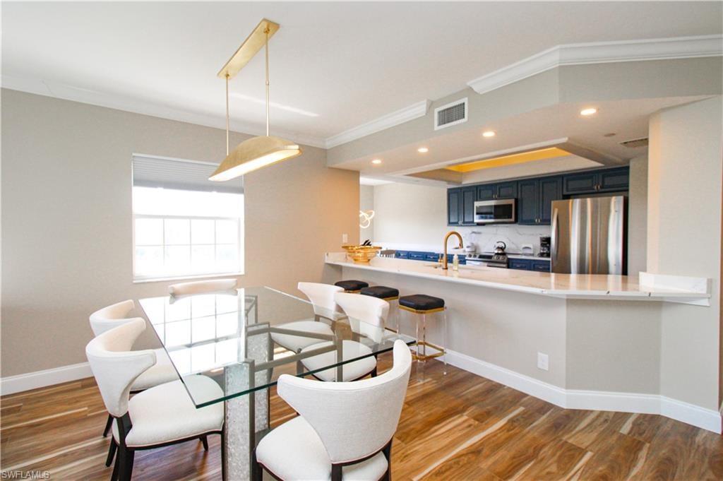 Dining room featuring ornamental molding, sink, and dark hardwood / wood-style flooring