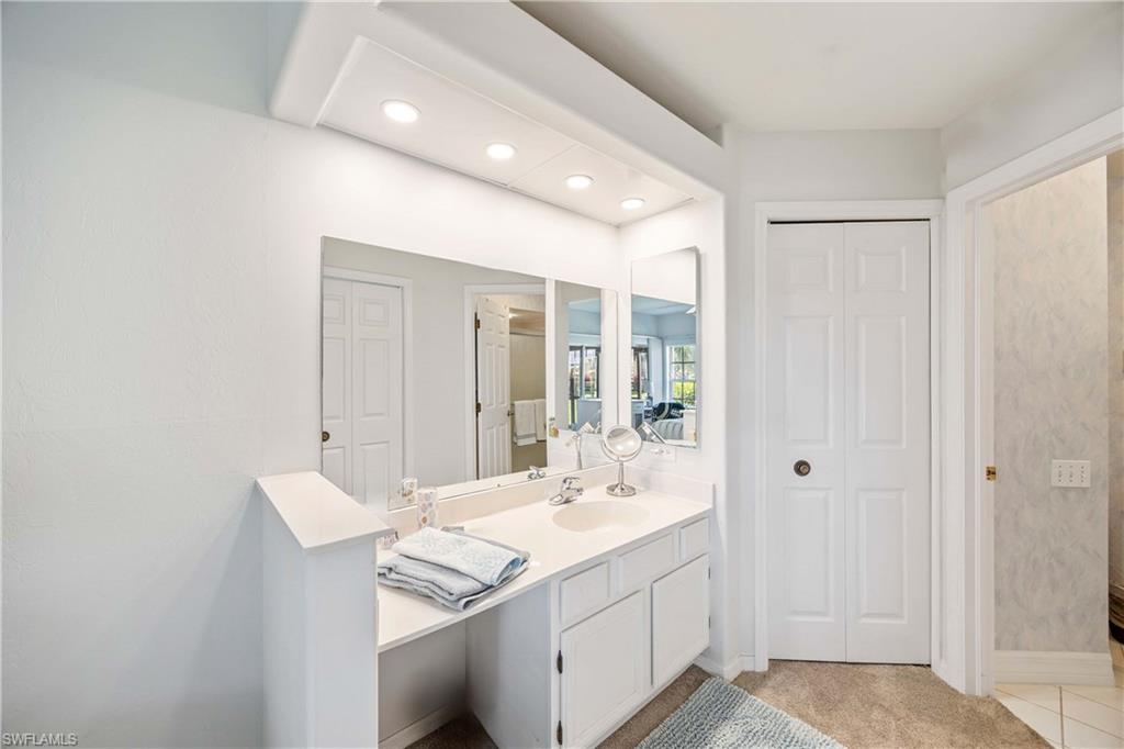 Bathroom with a closet, vanity, recessed lighting, and baseboards