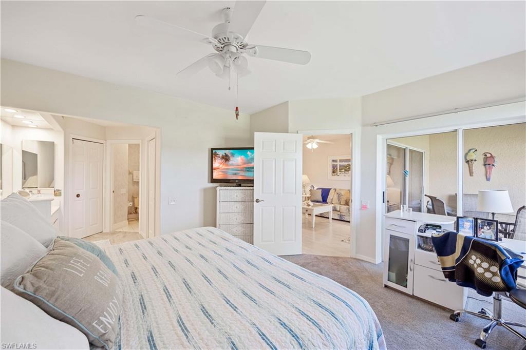 Bedroom featuring light carpet, ensuite bath, ceiling fan, and baseboards