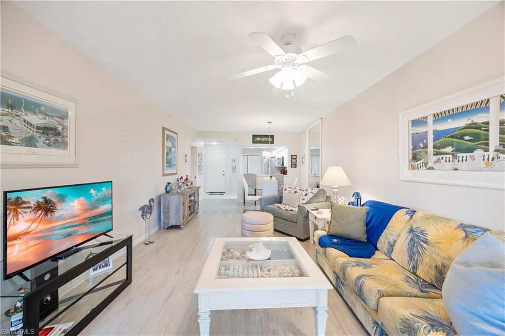 Living room with light wood-style floors, a ceiling fan, and baseboards