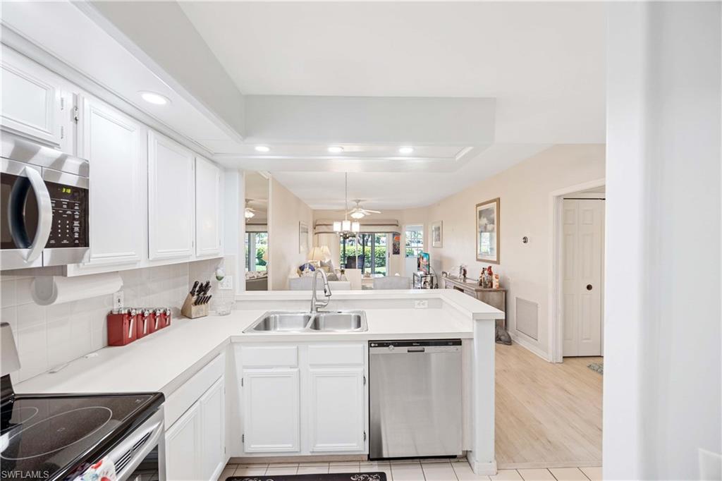 Kitchen featuring stainless steel appliances, a peninsula, a sink, recessed lighting, and light countertops