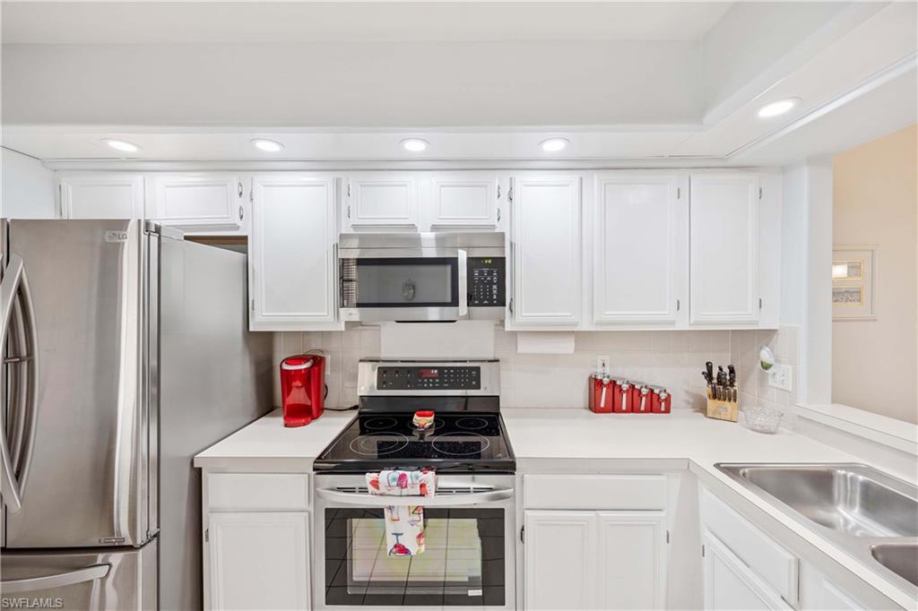 Kitchen featuring appliances with stainless steel finishes, light countertops, white cabinets, recessed lighting, and backsplash