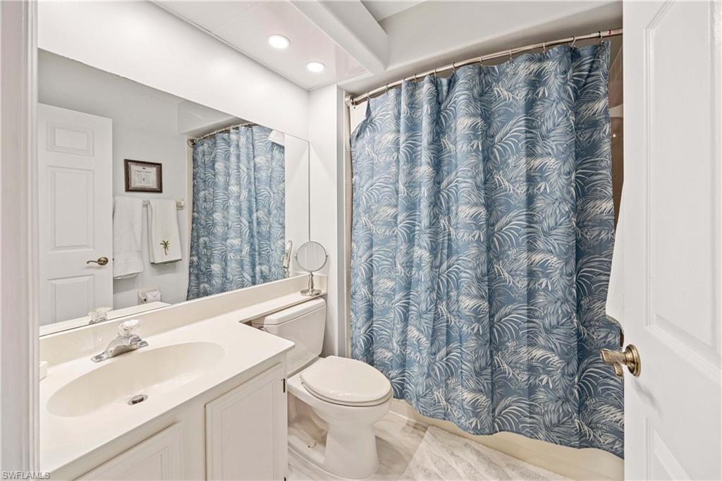 Full bath with toilet, vanity, recessed lighting, and curtained shower