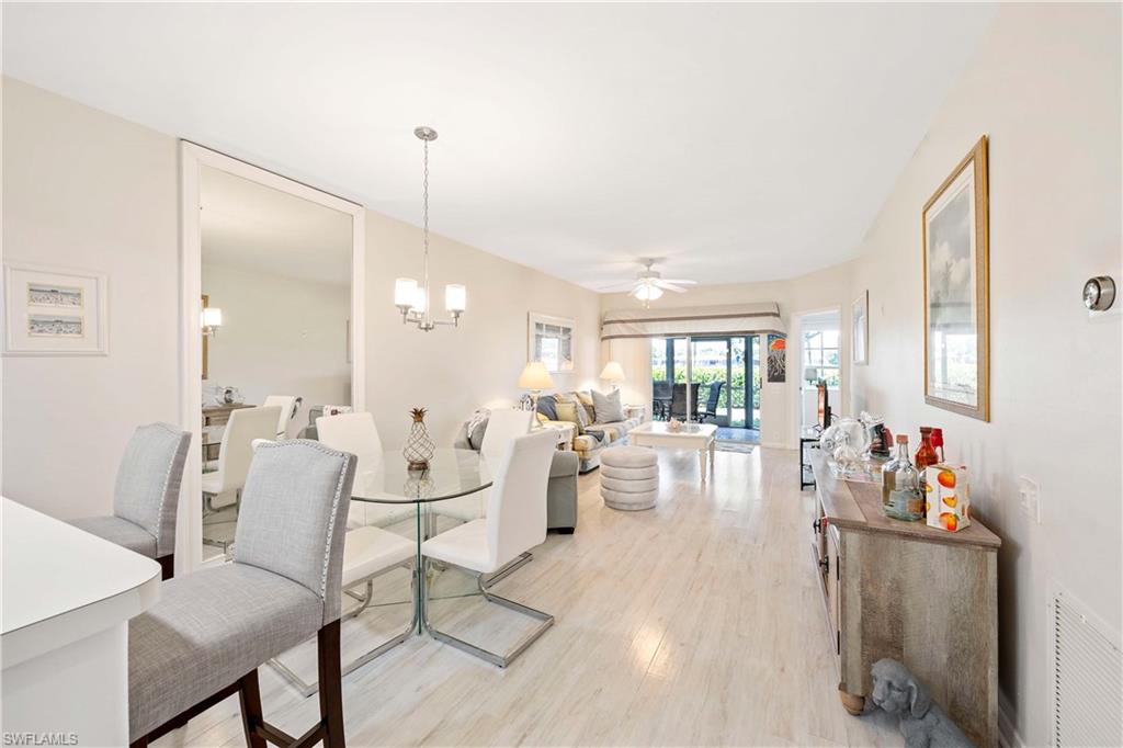 Dining room featuring light wood-type flooring, a chandelier, and a ceiling fan