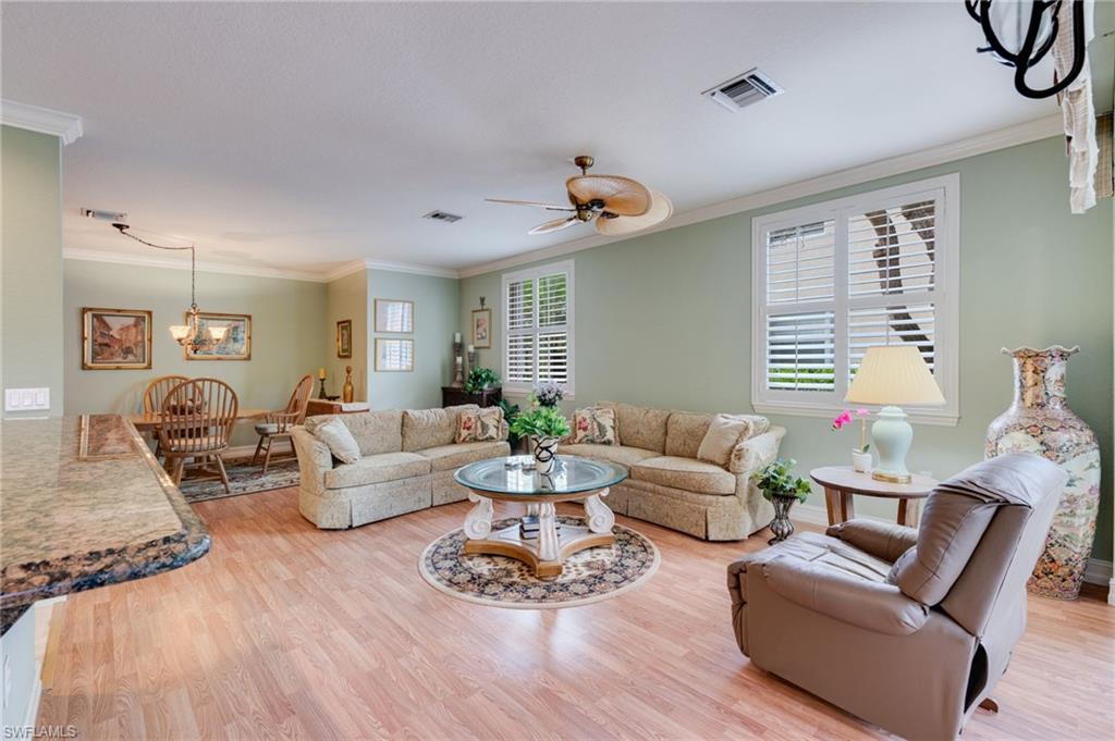 Living room featuring crown molding, a ceiling fan, light wood-style flooring, and hanging lights