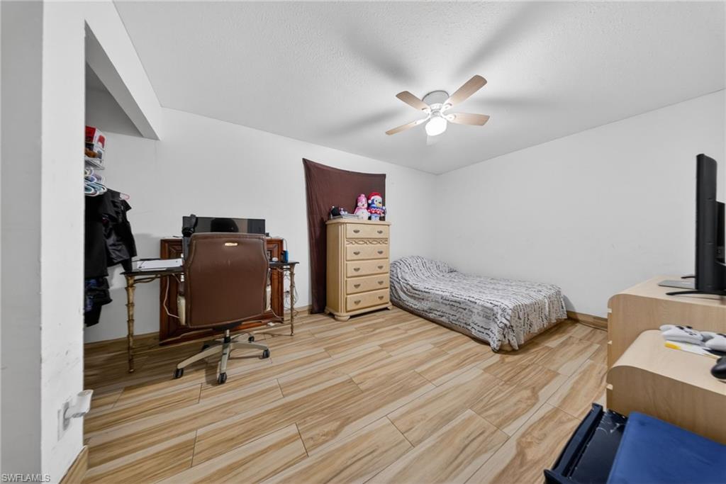 Bedroom with an office area, a ceiling fan, and light wood-type flooring