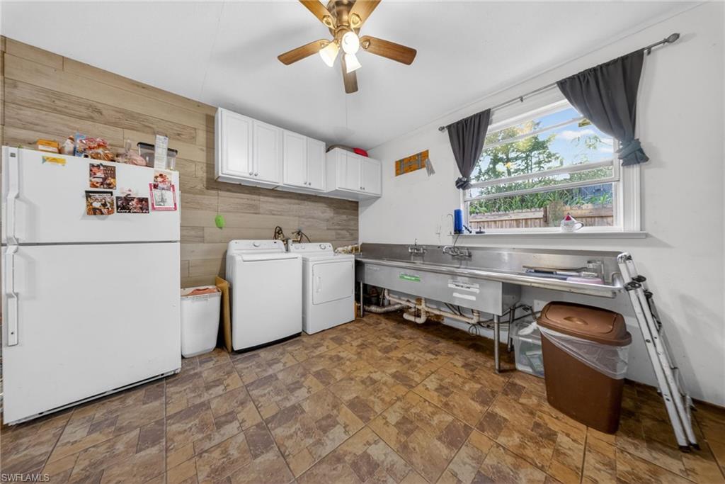 Laundry room with a ceiling fan, washing machine and clothes dryer, stone finish floors, and wood walls