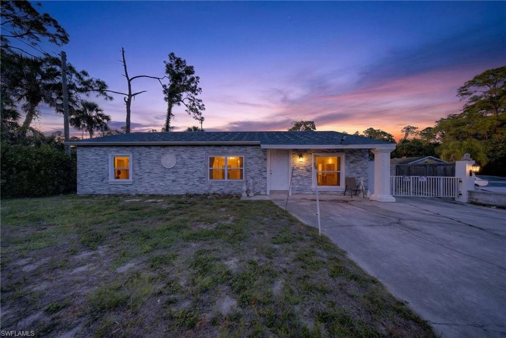 View of front of home featuring stone siding, driveway, a front yard, and a patio area