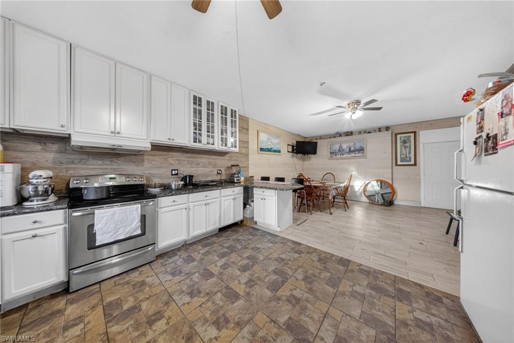 Kitchen featuring stainless steel range with electric cooktop, ceiling fan, freestanding refrigerator, glass fronted cabinets, and white cabinetry