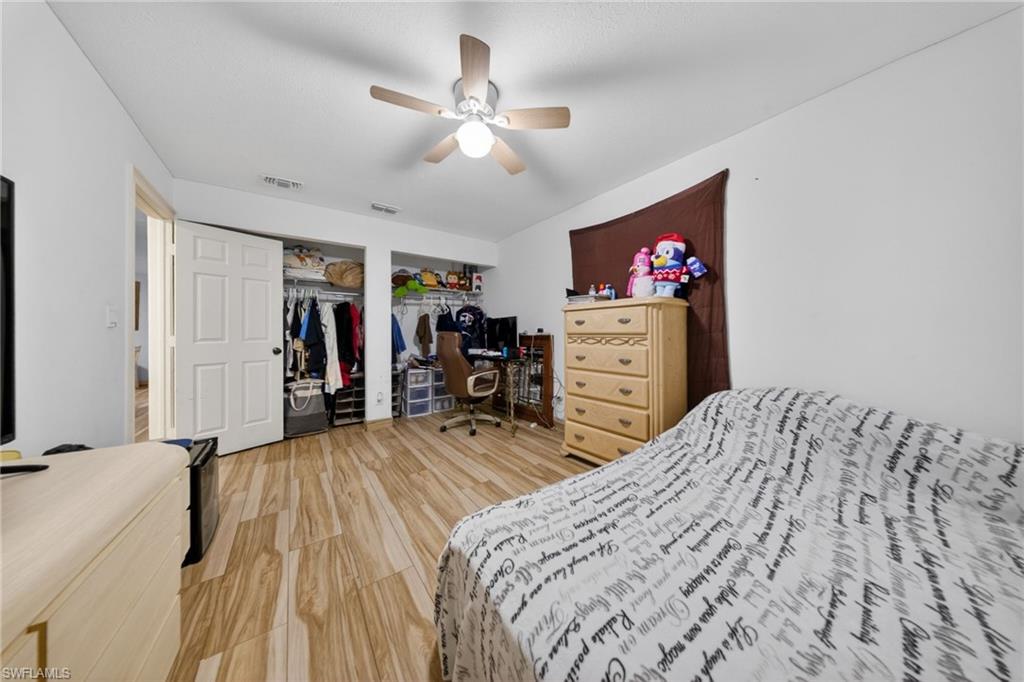 Bedroom featuring ceiling fan, light wood-style floors, and a desk