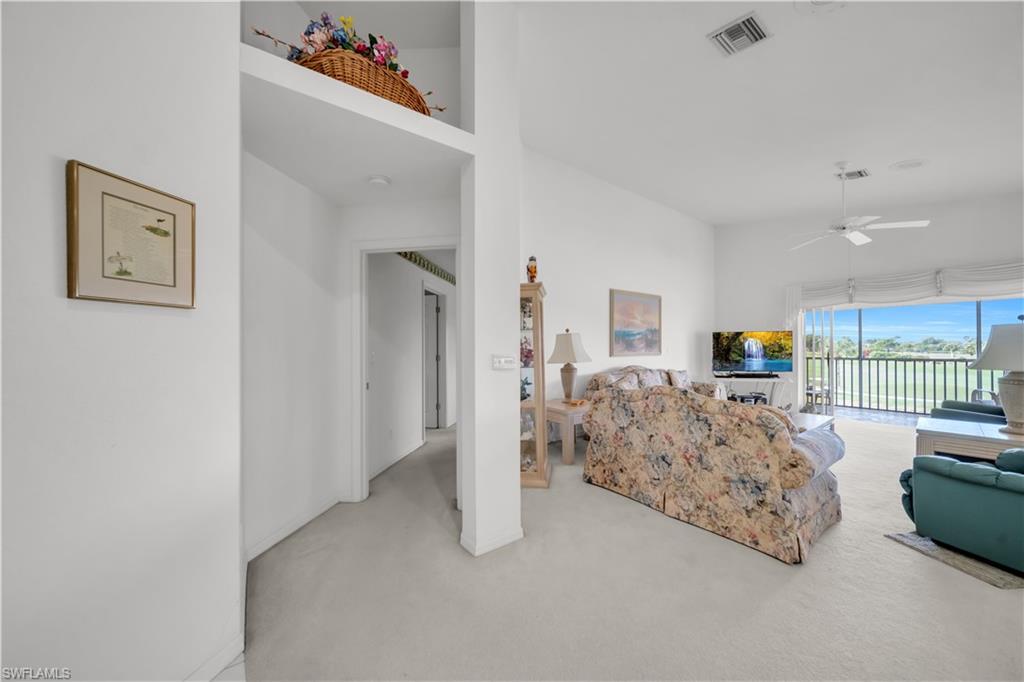 Living room with a high ceiling, ceiling fan, and light carpet
