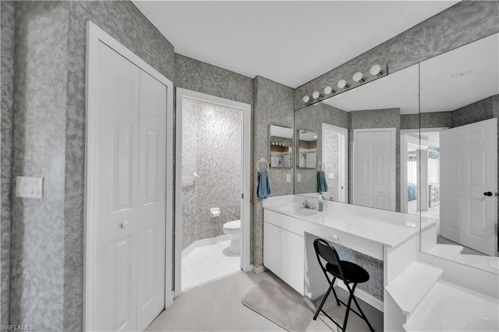 Full bathroom with a closet, vanity, and wallpapered walls