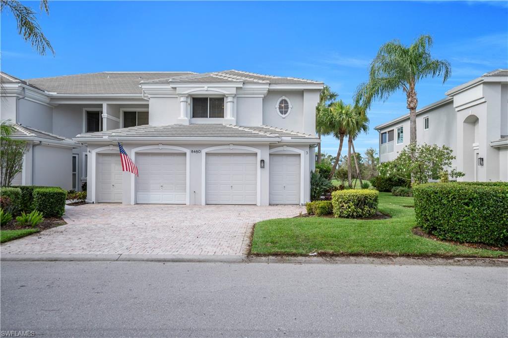 View of front of home featuring decorative driveway, stucco siding, a tiled roof, a front yard, and an attached garage