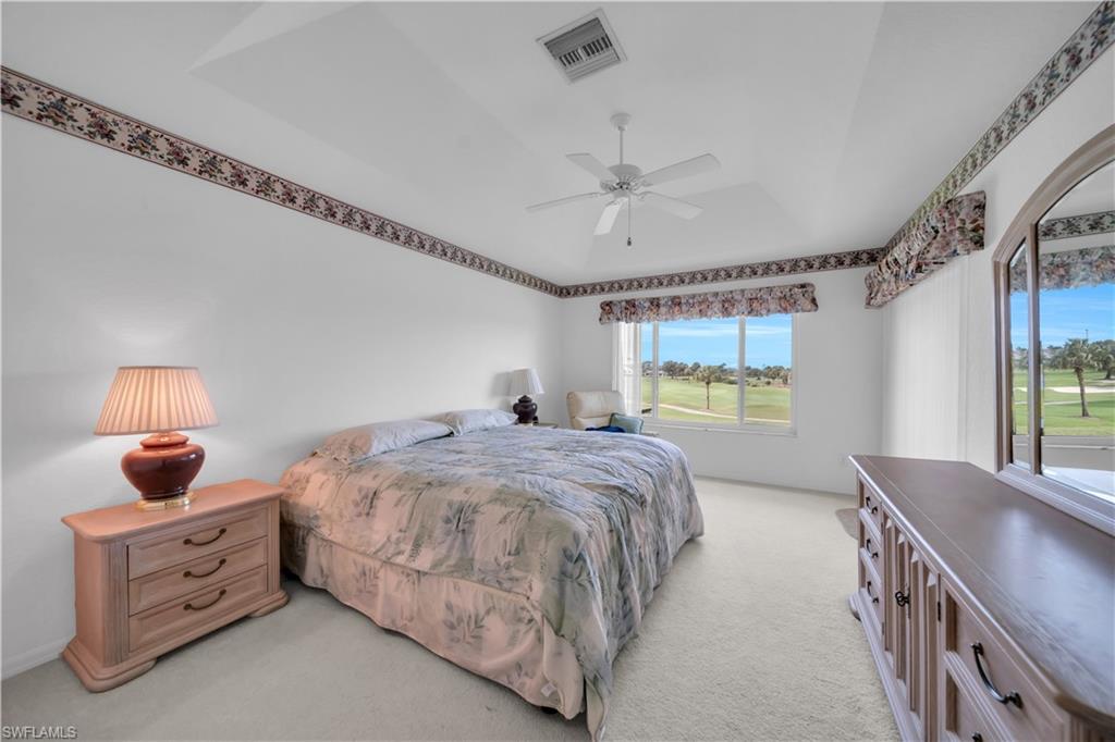 Bedroom featuring light colored carpet, ceiling fan, and golf course view