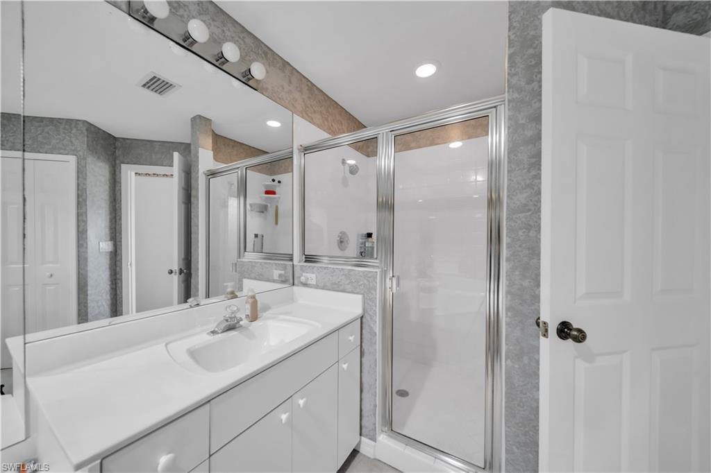 Bathroom featuring vanity, a stall shower, recessed lighting, and wallpapered walls