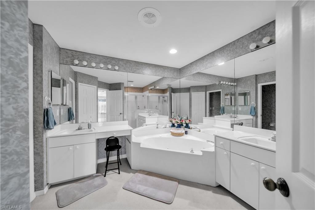 Bathroom featuring two vanities, a garden tub, recessed lighting, and wallpapered walls