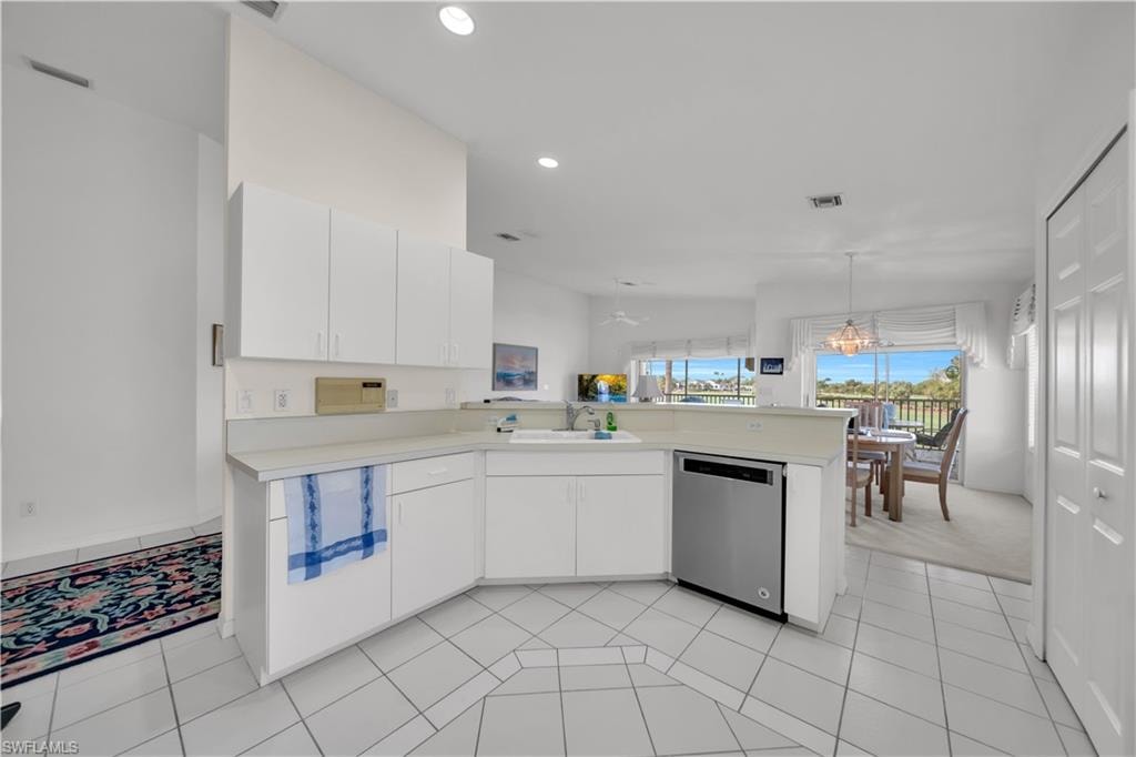 Kitchen with light countertops, a peninsula, white cabinetry, dishwasher, and pendant lighting