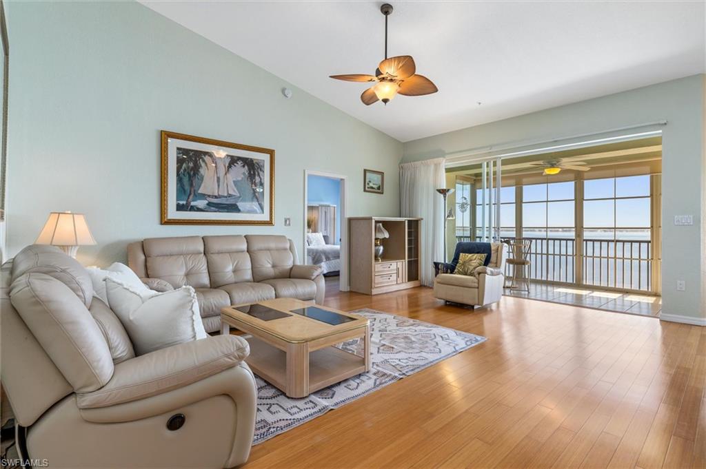 Living room with a ceiling fan, wood finished floors, and cathedral ceiling