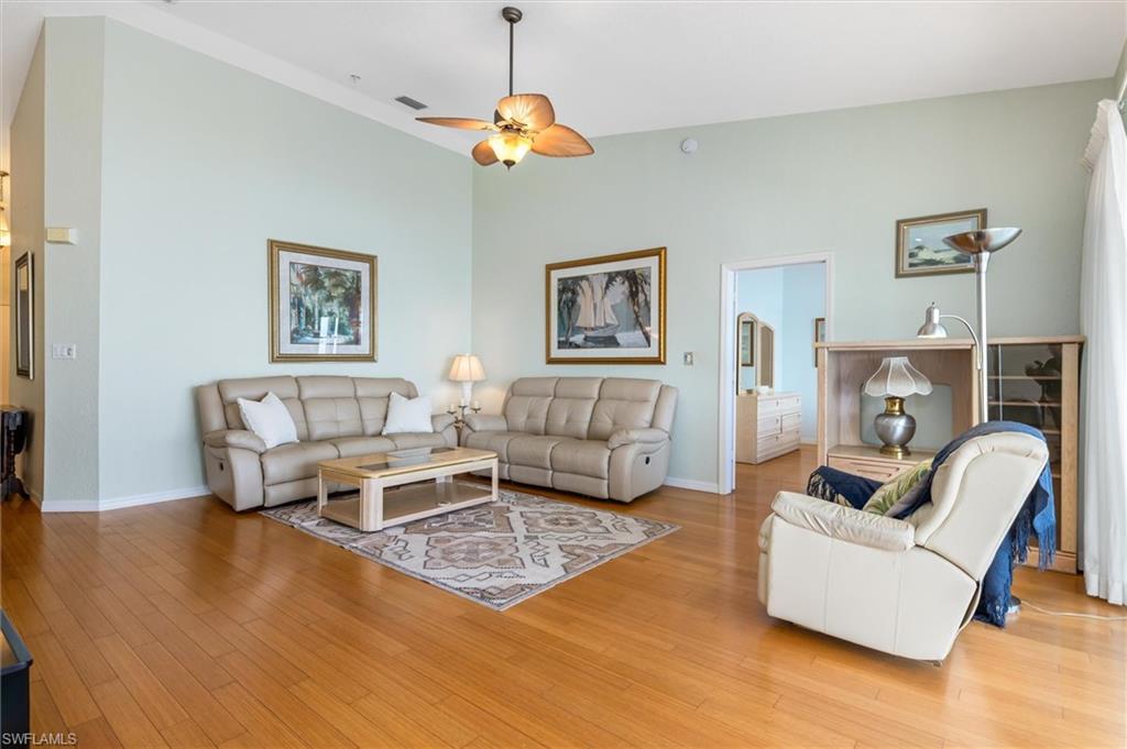 Living area with bamboo wood floors, a ceiling fan, and vaulted ceiling