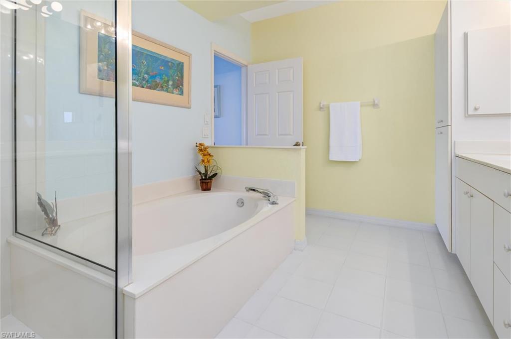 Primary ensuite bathroom with dual vanity, bath tub, walk-in shower and linen closet. Ceramic tile floor.