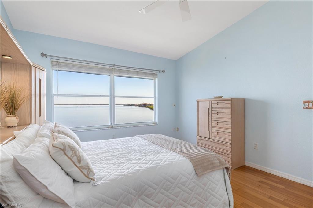 Bedroom with vaulted ceiling, wood flooring, ceiling fan, walk-in closet, and ensuite bathroom