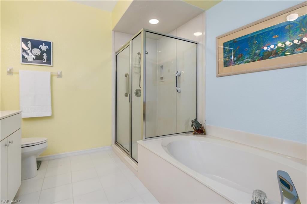 Primary ensuite bathroom with dual vanity, garden tub, walk-in shower and linen closet. Ceramic tile floor.