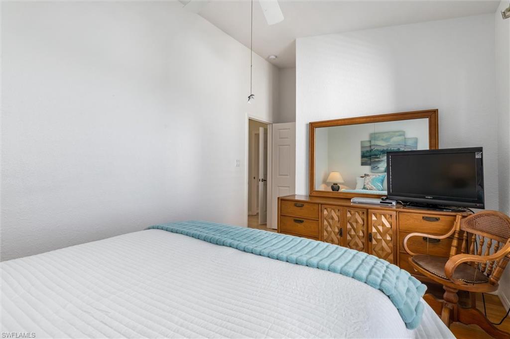 Guest bedroom with wood floors, ceiling fan, walk-in closet and lofted ceiling