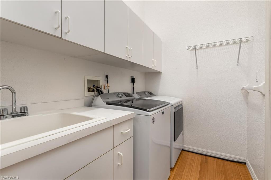 Interior laundry room featuring cabinets, utility sink, washer, dryer and utility storage closet