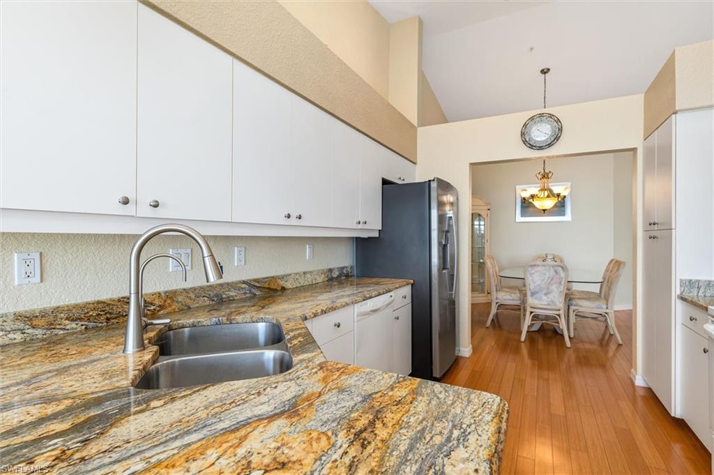 Kitchen with stone counters, white cabinets, a peninsula, wood floors, and ceiling fan