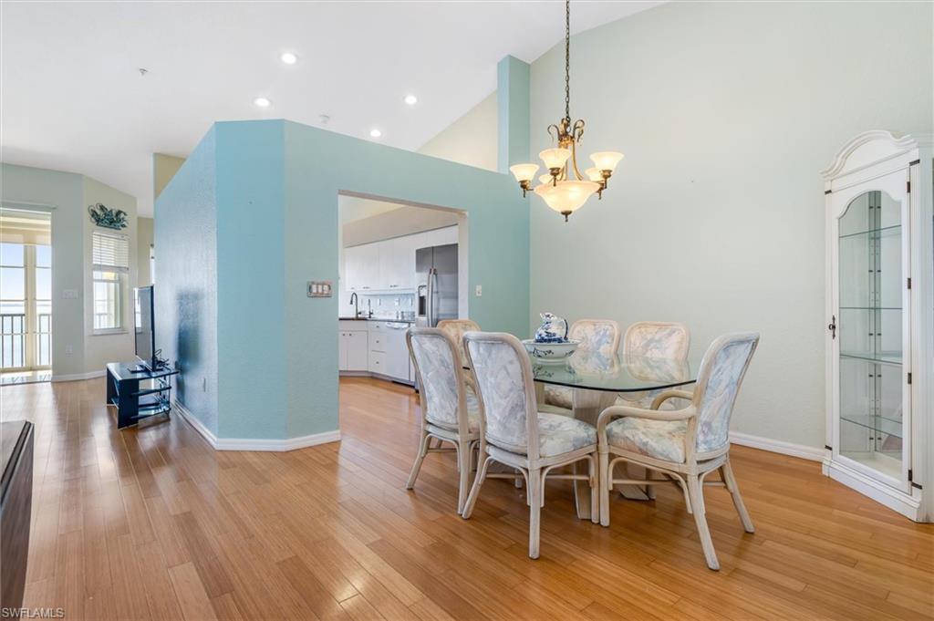 Dining room featuring vaulted ceiling, hanging lights, and wood floors
